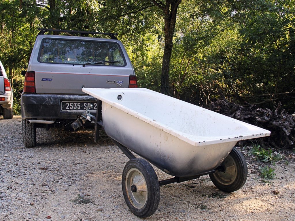 Auto mit Anhänger, wobei der Anhänger eine alte Badewanne ist.