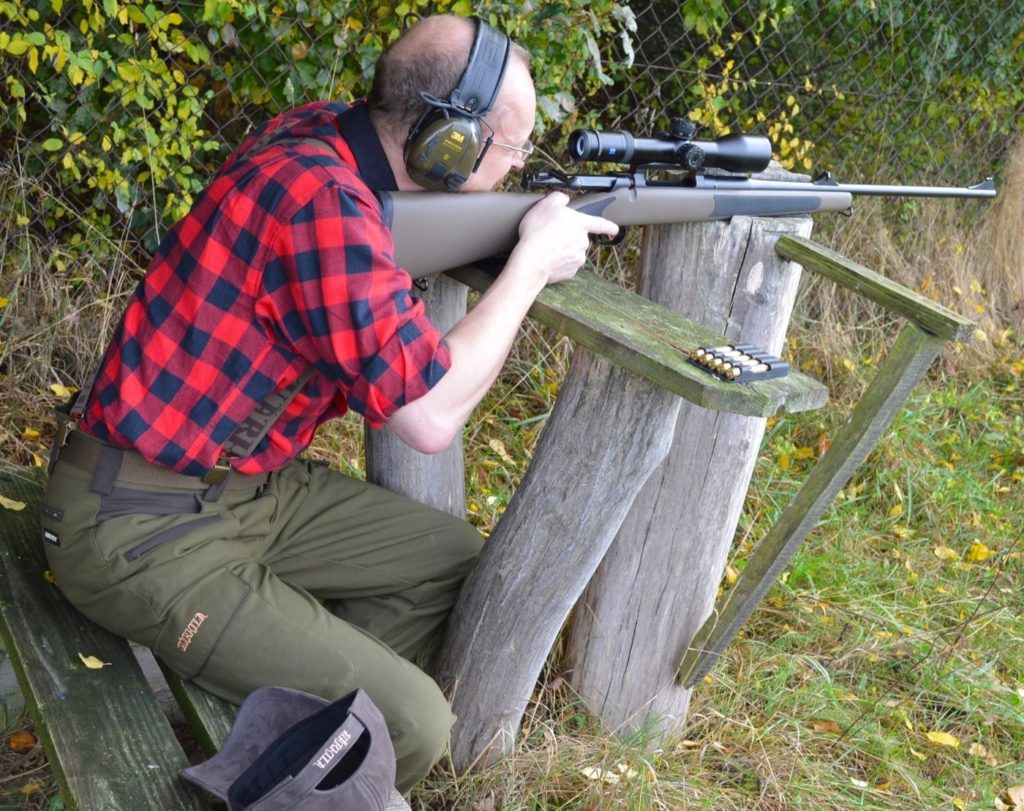 Jäger legt auf einem Stumpf auf und nimmt Ziel.