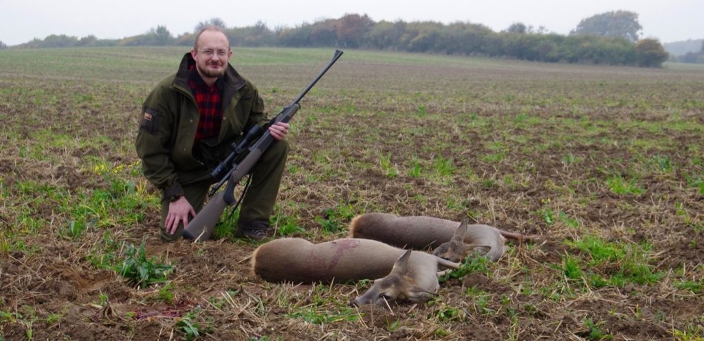 Jäger kniet neben zwei geschossenen Rehkühen.