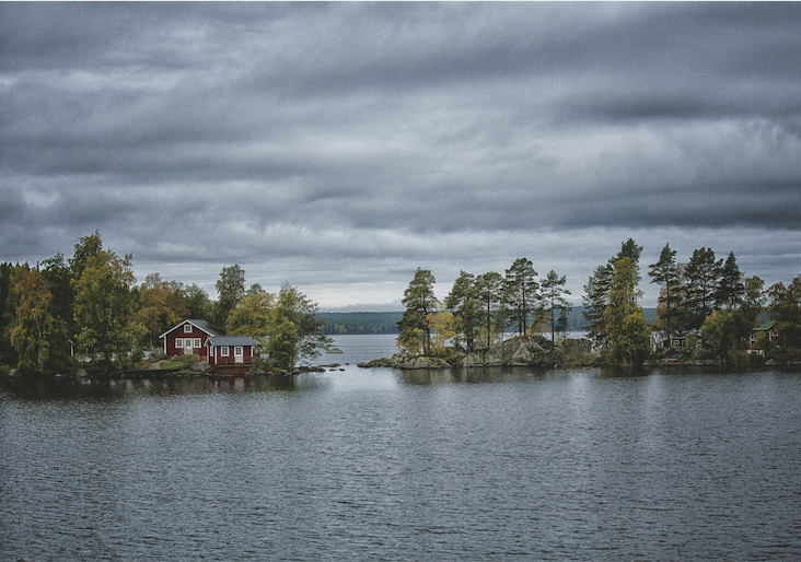 Schwedenhaus am See in grüner Landzunge.